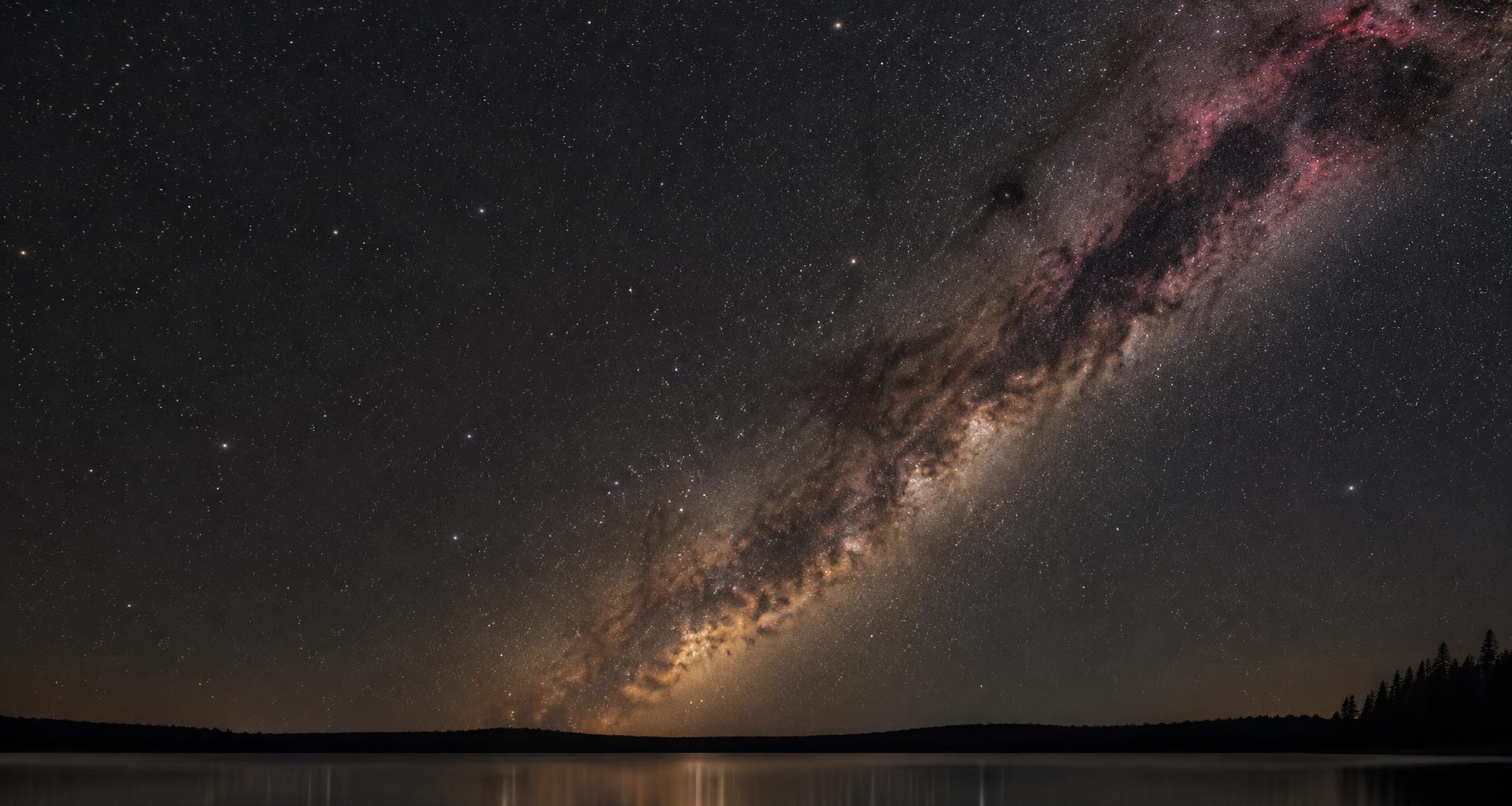 The Milky Way stretching across a star-filled sky above a quiet lake